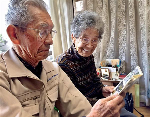 在りし日の「飯田資料室」の写真を眺める義昭さん、喜久代さん夫妻＝２７日、山口県周南市（大森貴弘撮影）